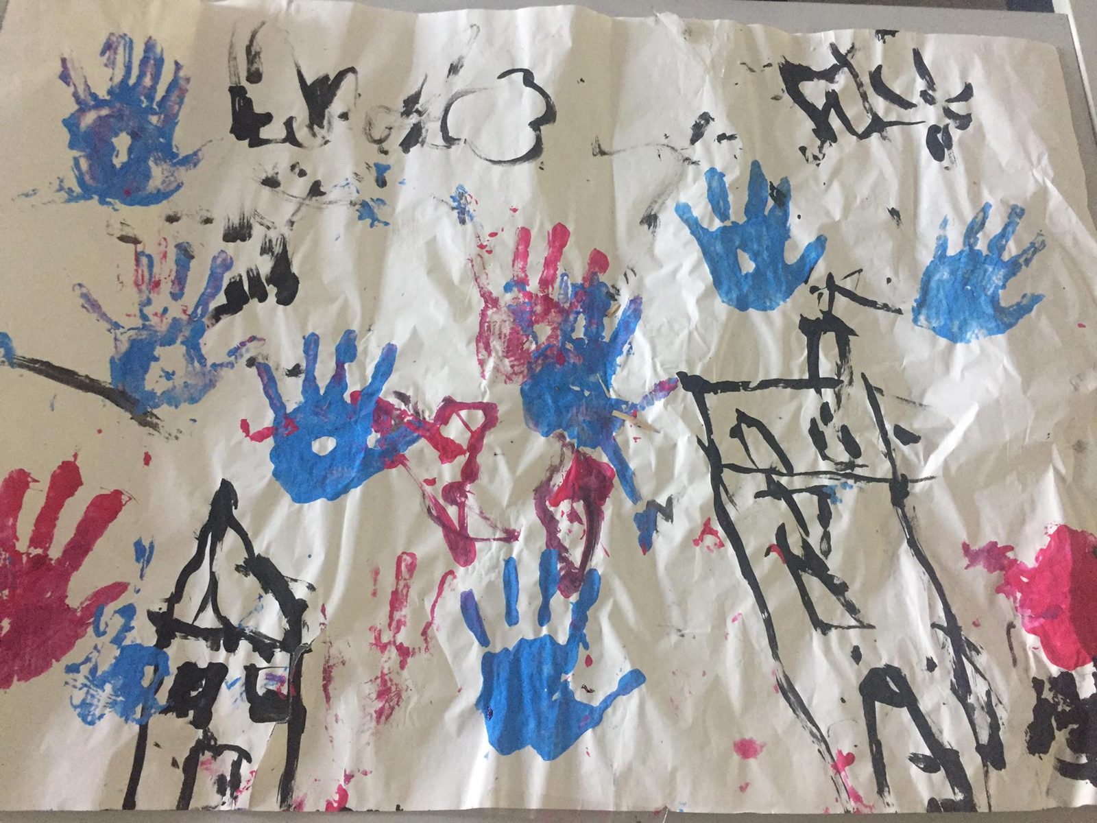 Pintura coletiva com marcas de mãos de crianças em azul e rosa